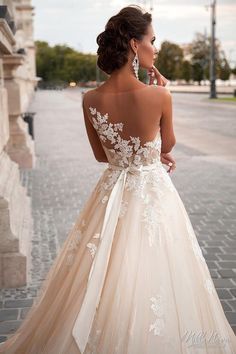 a woman in a wedding dress with a bow on her back looking at the street