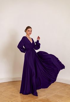 a woman in a long purple dress posing for the camera