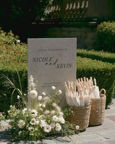 two baskets filled with flowers and umbrellas next to a sign that reads nicole of kevin