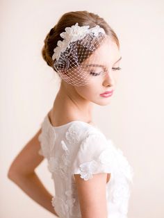 a woman wearing a veil with flowers on the head and hair comb in her hand