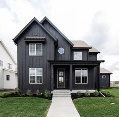 a black house with white trim on the front and side windows is shown in this photo