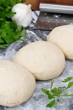 three uncooked doughnuts sitting on a table next to some parsley