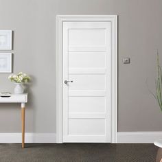 an empty room with a white door in the center and two pictures on the wall