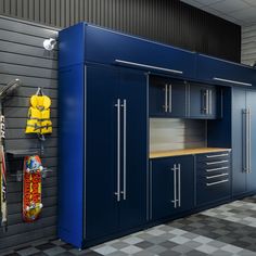 a garage with blue cabinets and skateboards on the wall next to it, in front of a checkered floor