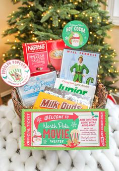 a basket filled with christmas movies next to a christmas tree