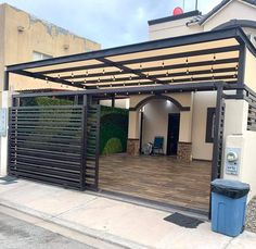 an outdoor covered patio with a trash can and garbage can in front of the building