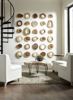 a living room filled with white furniture and lots of plates on the wall above it