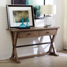 a wooden table with two vases and a framed photograph on it next to a window