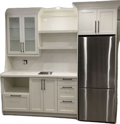 a refrigerator freezer sitting inside of a kitchen next to white cupboards and cabinets