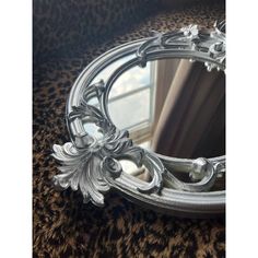 an ornate silver mirror sitting on top of a leopard print rug next to a window