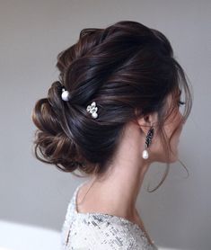 a woman with her hair up in a low bun and pearls on the side of her head