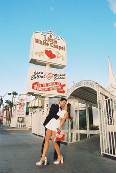 two people are kissing in front of a sign for a little white chapel restaurant and casino