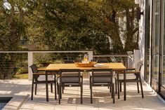 a table and chairs on a patio with trees in the background