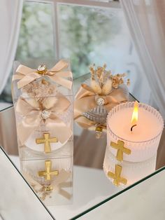 two candles are sitting on a glass table next to each other with bows and crosses