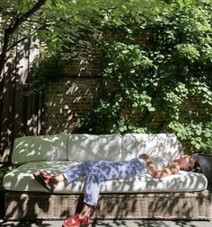 a man laying on top of a white couch under a tree