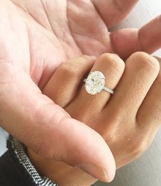 a person holding an engagement ring in their hand with the diamond on it's finger