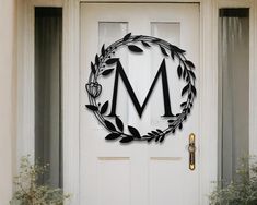 a metal wreath with the letter m on it is mounted to a white front door