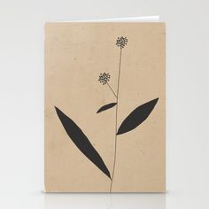 a card with black leaves on it and a flower in the middle, against a beige background