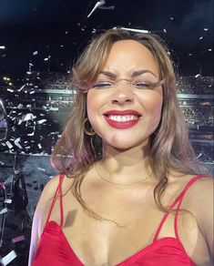 a woman in a red dress is smiling and confetti flies around her head