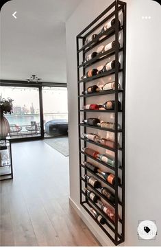 a wall mounted wine rack filled with bottles in a living room next to a window