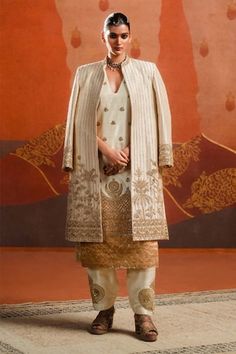 Ivory jacket with stripe, palm tree, floral, house motifs gold embroidery using sequins, cutdana. Paired with an inner kurta with house motifs, crescent moon, trellis embroidery in gold tones using sequins, cutdana. Paired with a poncha style salwar with gold motif embroidery. - Aza Fashions Moon Jacket, Raw Silk Embroidery, Jacket Cape, Kurta Set For Women, Gold Embroidery, Silk Embroidery, Kaftan Dress, Kurta Set, Only Fashion