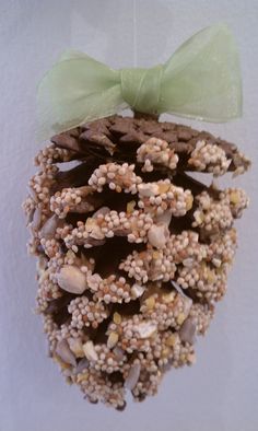 a pine cone ornament with a green bow hanging from it's side