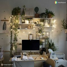 a desk with a computer on top of it surrounded by plants and other things in the room