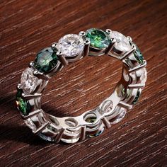 a close up of a ring on a table with green and white stones in it