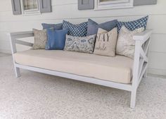 a white couch with blue and gray pillows on it's backrest in front of three framed pictures