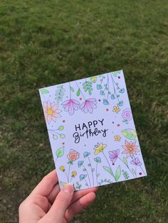 someone holding up a card that says happy birthday with flowers and butterflies on the front