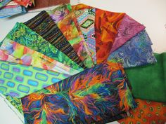 a bunch of different colored fabrics on a table