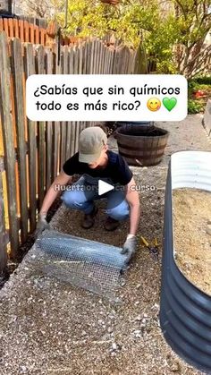 a man kneeling down in front of a fence next to a trash can and an empty container