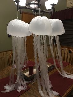 some lights that are hanging from the ceiling over a dining room table with jellyfish decorations on it