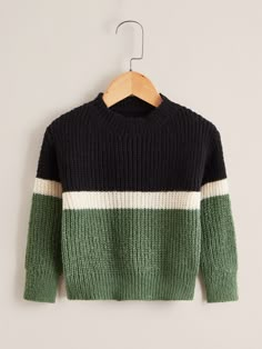 a green, black and white sweater hanging on a hanger with a wooden hanger