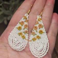 a pair of beaded earrings in the palm of someone's hand