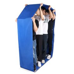 three people standing in a blue structure with their hands on the top