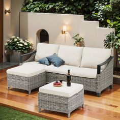 an outdoor living room with wicker furniture and potted plants