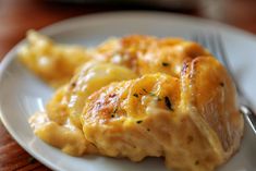 a white plate topped with meat and cheese covered in gravy next to a fork