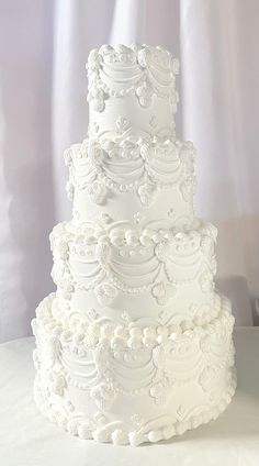 a three tiered white wedding cake sitting on top of a table