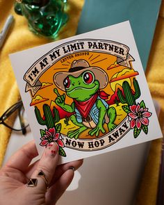 Personalize your belongings with our Kiss Cut Sticker. This high-quality water bottle sticker showcases a cute frog cowboy flipping the bird against a tattoo-style desert scene with cacti and flowers. 

Perfect to use as water bottle stickers, laptop stickers, and notebook stickers, it's an ideal choice for frog lovers, introverts, and fans of funny frog memes. Add a touch of cottagecore charm and western aesthetic to your everyday items with this quirky and humorous sticker. Flipping The Bird, Funny Frogs, Western Aesthetic, Cute Frog, Cowboy Art, Stickers Laptop, Notebook Stickers