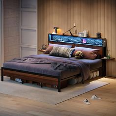 a bed sitting on top of a wooden floor next to a night stand with lights