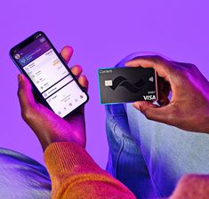 a person holding a cell phone and a credit card in their hand while sitting down