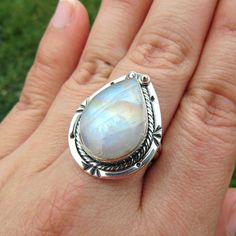 SKU: SS-061Material: 925 stamped sterling silverGemstone(s): Rainbow Moonstone (N)Gemstone Dimensions: 13 X 19 X 4 mmRing Size: US 8Weight: 8.1 gramsThis eye-catching Rainbow Moonstone ring features a teardrop Rainbow Moonstone cabochon, set in a classic bezel with a modern braid border that accents the stone beautifully. This Rainbow Moonstone lives up to its name, showcasing blue, orange and yellow fire all throughout the stone. Teardrop Moonstone Gemstone Ring, Handmade Moonstone Teardrop Ring, Silver Teardrop Moonstone Ring, Silver Pear-shaped Moonstone Ring, Adjustable Teardrop Moonstone Ring In Sterling Silver, Silver Teardrop Gemstones, Silver Teardrop Moonstone Ring In Sterling Silver, Sterling Silver Teardrop Moonstone Ring, Silver Teardrop Cabochon Rings