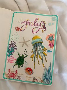 an open notebook with sea animals and jellyfishs on the cover is sitting on a bed