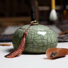 a teapot with a tassel on it sitting next to some other items in the background