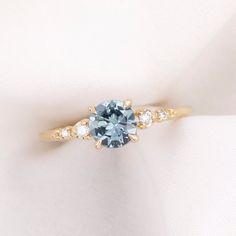 an engagement ring with a blue and white diamond in the center on a white cloth