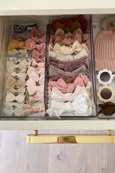 an open drawer filled with lots of clothes and sunglasses on top of a wooden floor