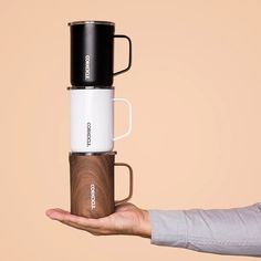 a person holding a coffee cup in one hand and a travel mug in the other