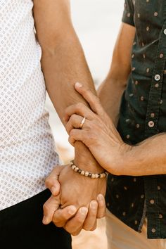 two people holding hands while standing next to each other with their hands on top of each other