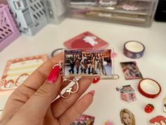 a person holding a cell phone in front of some stickers and magnets on a table